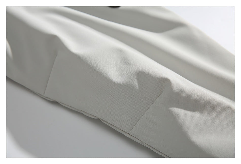 Close-up of a white jacket's stitched panel seam and smooth fabric.