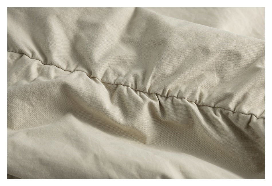 Close-up of beige garment fabric with a gathered, stitched seam and soft folds.