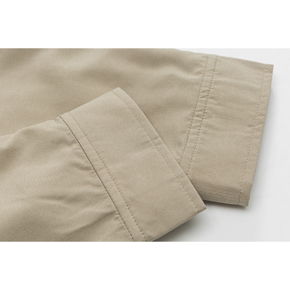 Close-up of a taupe shirt sleeve and wide button cuff.