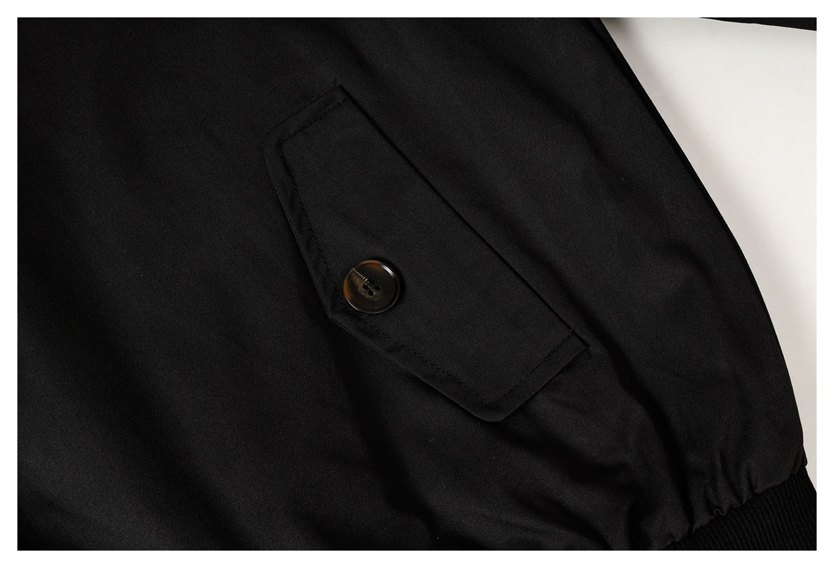 Close-up of a black jacket's buttoned flap pocket and ribbed edge.