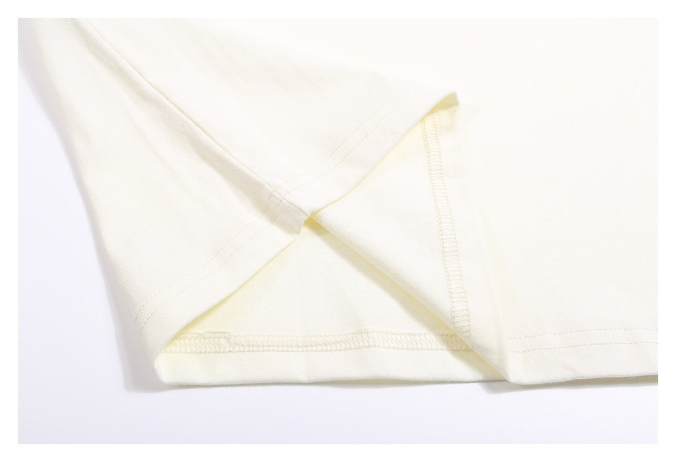 Close-up of the ivory T-shirt's inside seam, overlock stitching, and hem.