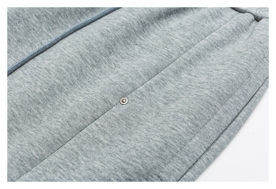 Close-up of a small metal eyelet set into heather gray pants fabric.
