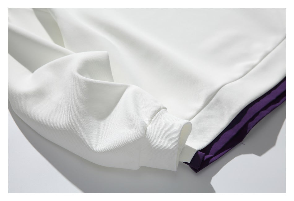 Close-up of the white sweatshirt's ribbed sleeve cuff and purple hem trim.