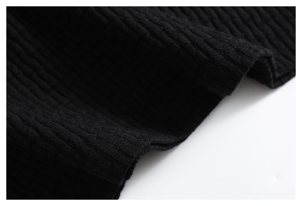 Close-up of the black ribbed garment's edge and stitching.