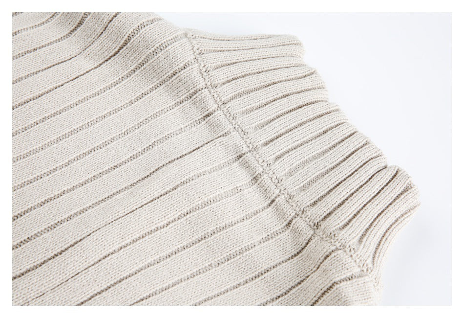 Close-up of the cream rib-knit garment's shoulder and armhole seam.