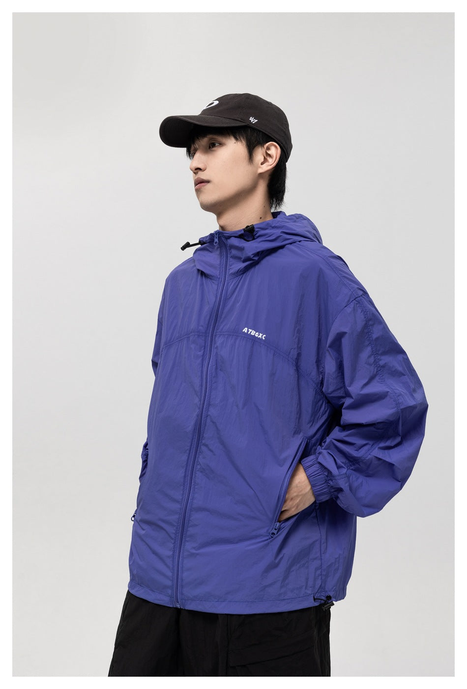 Three-quarter view of a model wearing a blue-violet hooded zip jacket with black shorts.