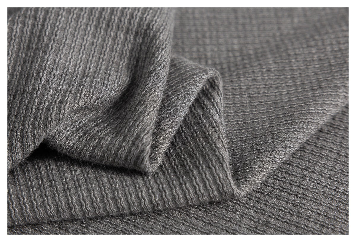 Close-up of folded gray fabric showing its raised, wavy knit texture.