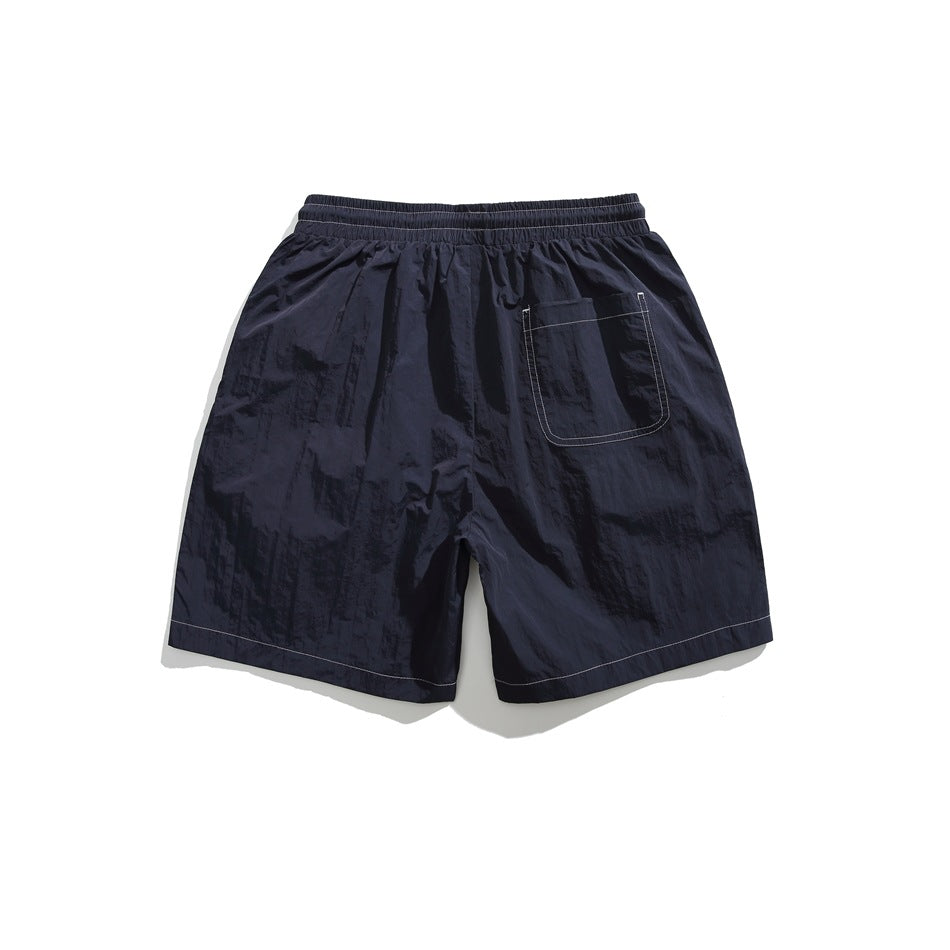 Rear view of dark navy shorts with an elastic waistband, a back patch pocket, and contrast stitching.