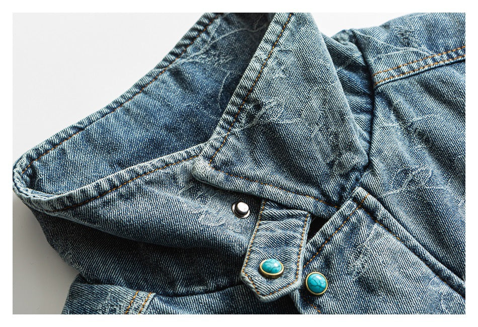 Close-up of blue denim with orange stitching and turquoise decorative buttons.