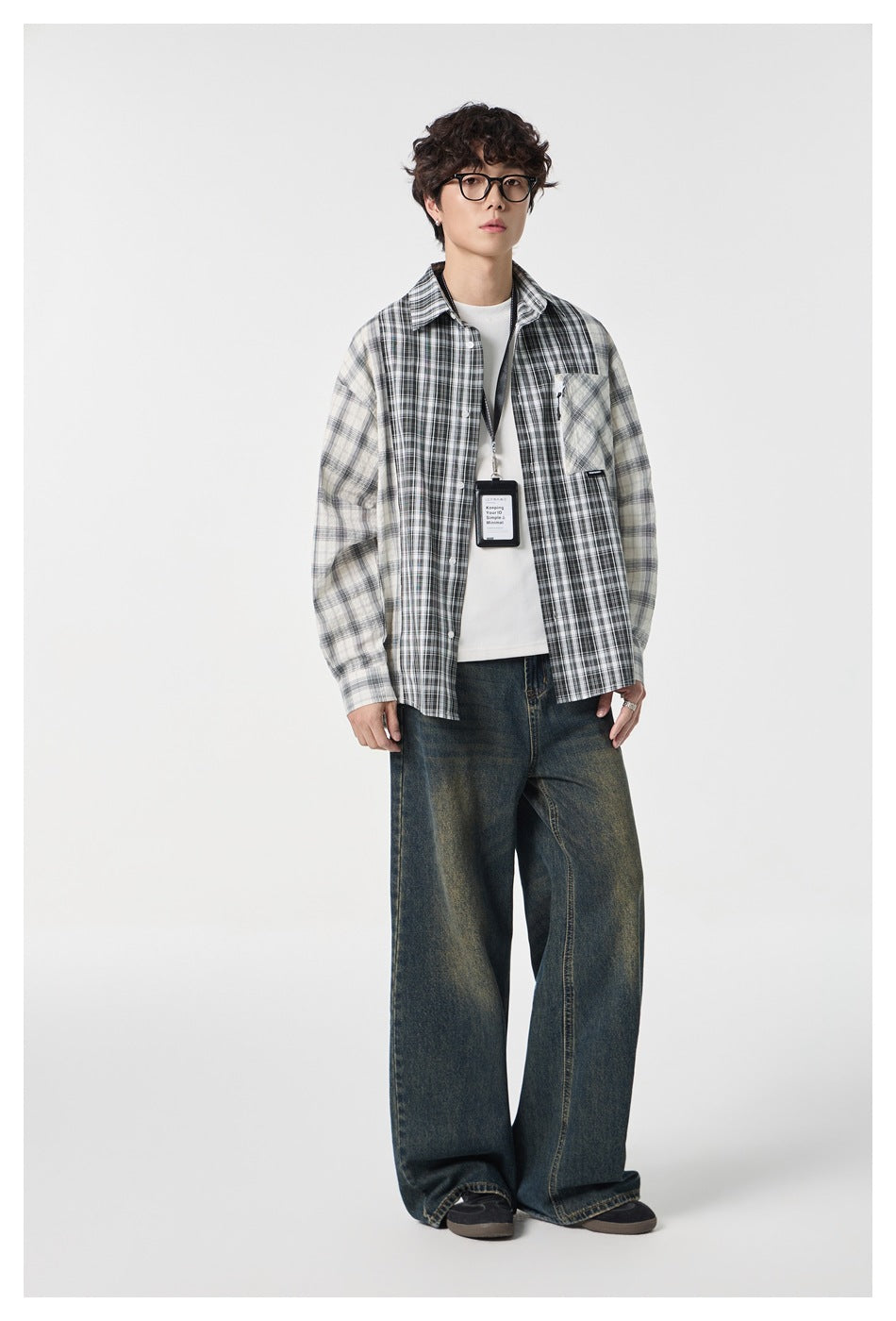 Full-length front view of a model in a black and cream mixed-plaid shirt and wide-leg jeans.