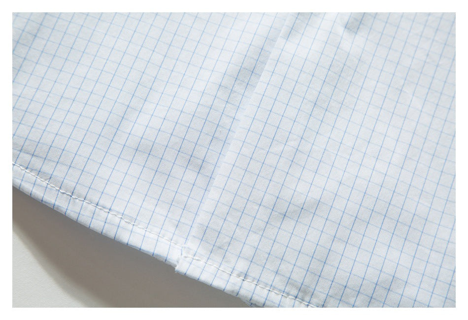 Close-up of the hem stitching on a white shirt with a light blue grid pattern.
