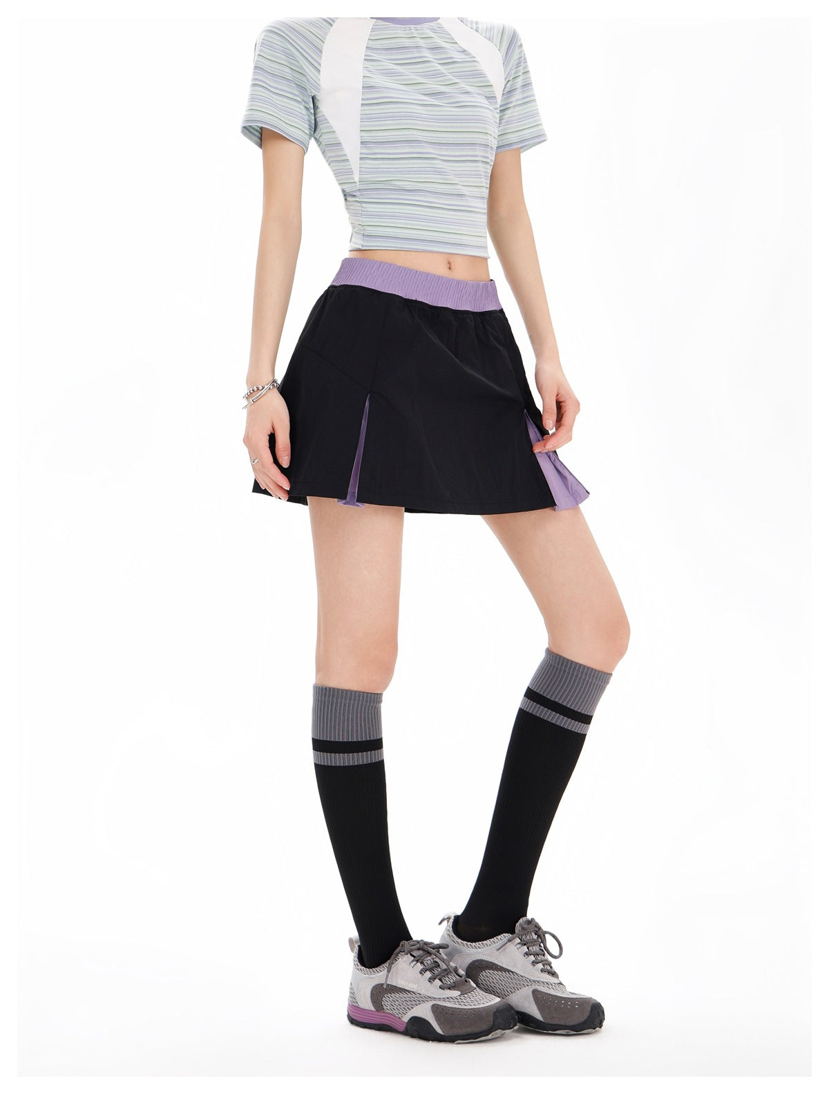 Front view of a model wearing a black flared skirt with a lavender waistband and lavender side panels.
