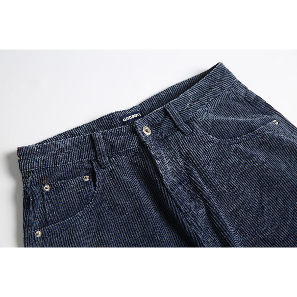 Close-up of navy ribbed pants showing the waistband, front button, belt loops and front pockets.