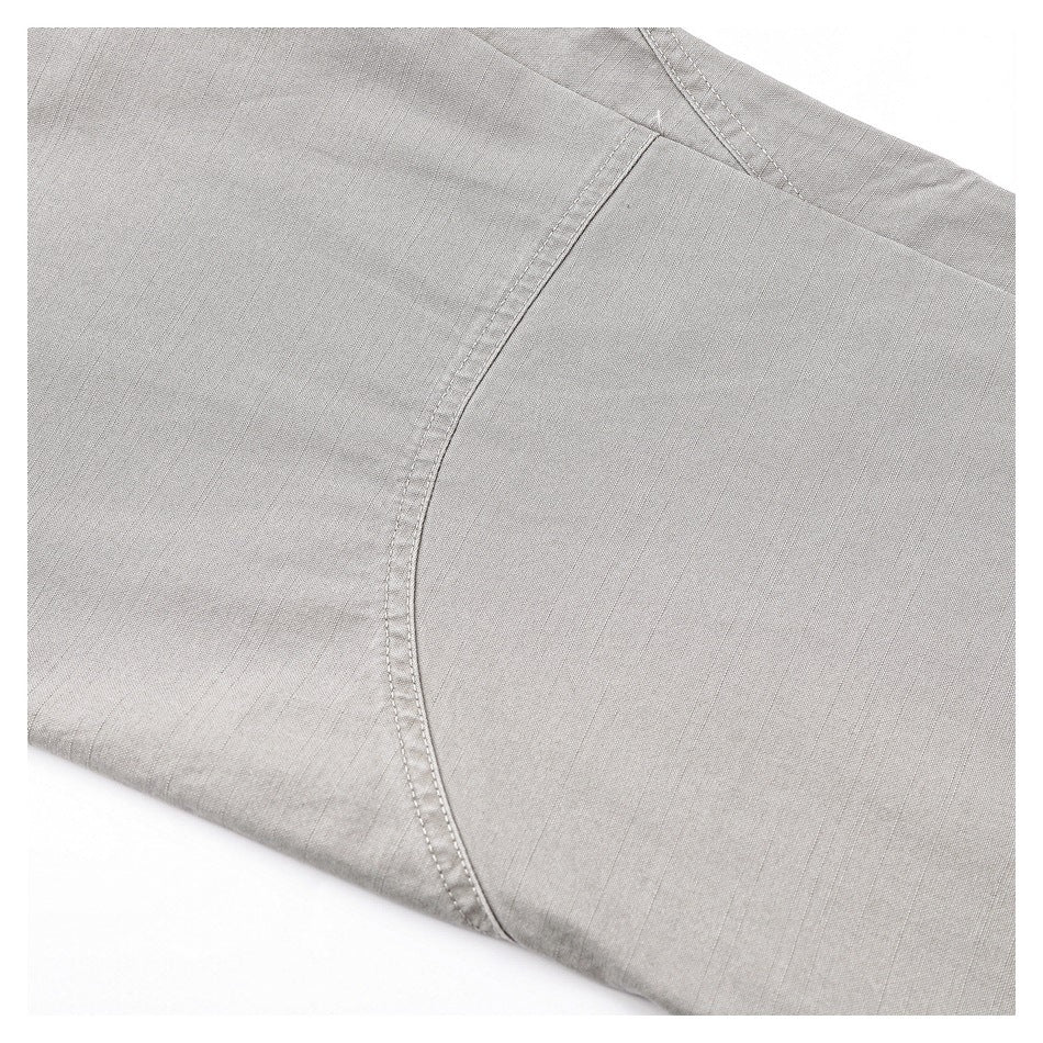 Close-up of a curved stitched seam and panel on the light gray trouser fabric.