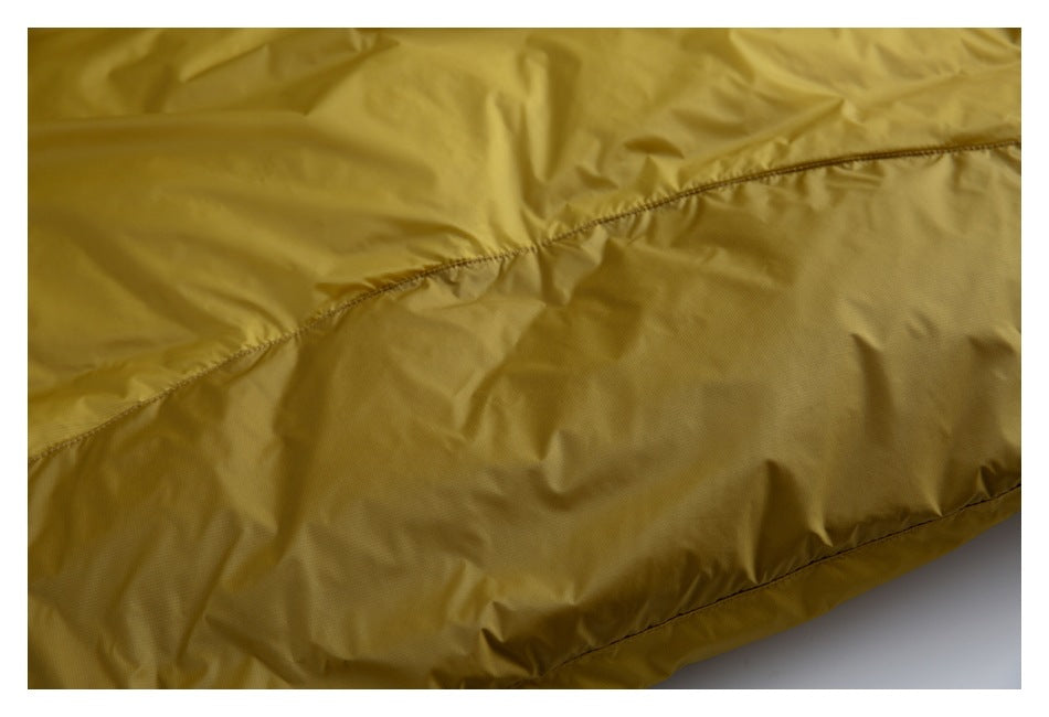 Close-up of mustard-yellow garment fabric with curved stitched seams and a hem.