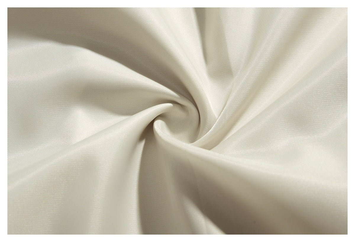 Macro view of off-white fabric gathered into a swirl, showing its fine woven texture.