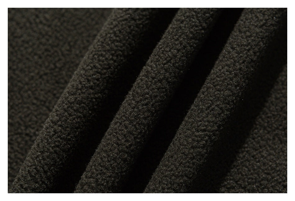 Close-up of dark garment fabric showing a dense, nubby texture and soft folds.
