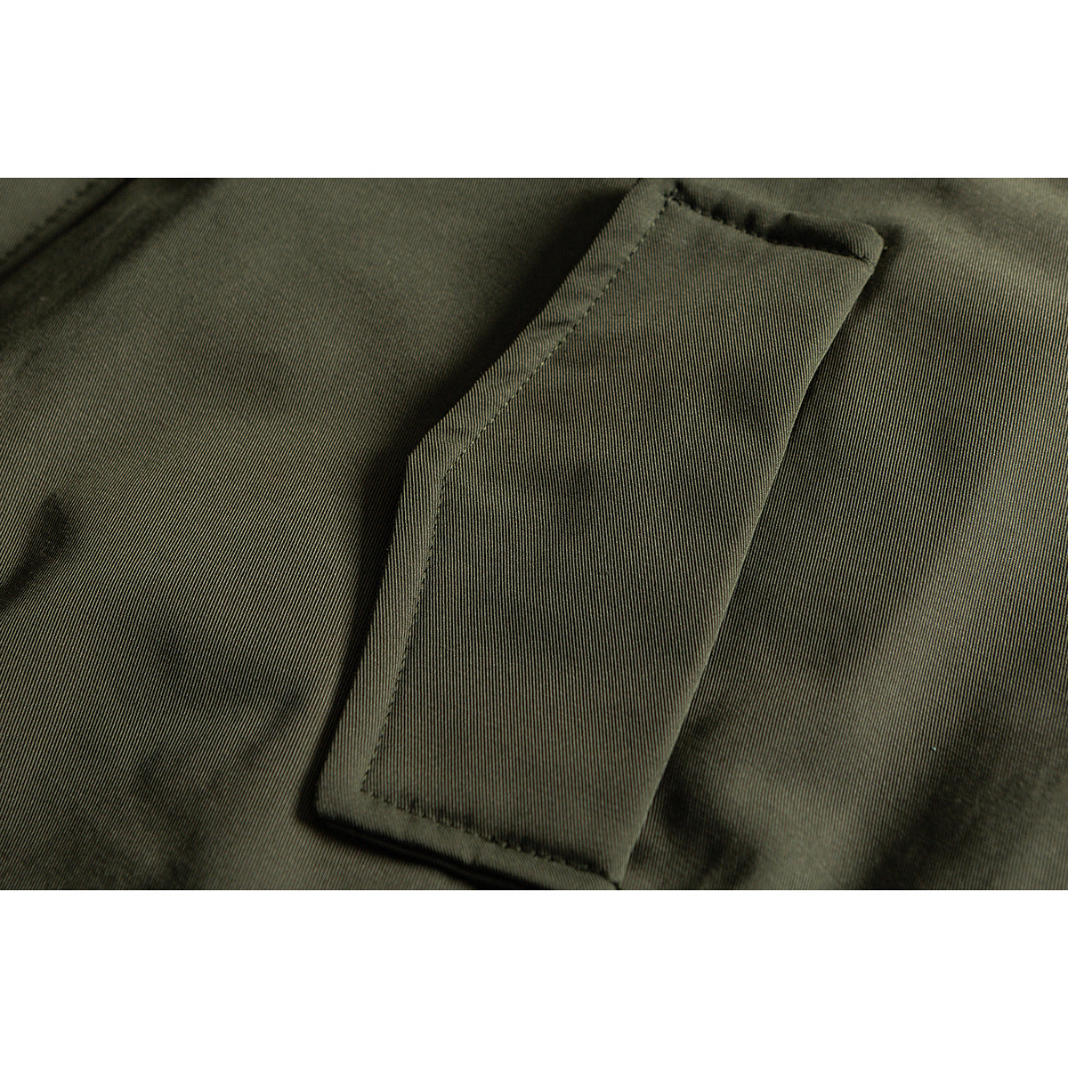 Close-up of a rectangular pocket on olive fabric, showing its stitching and flap.