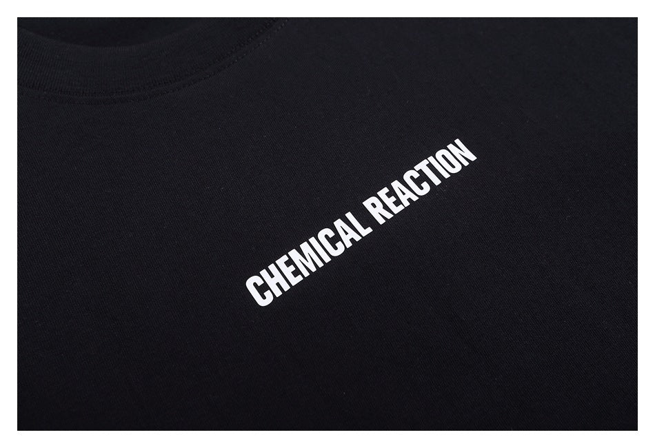 Close-up of white CHEMICAL REACTION lettering printed on black T-shirt fabric.
