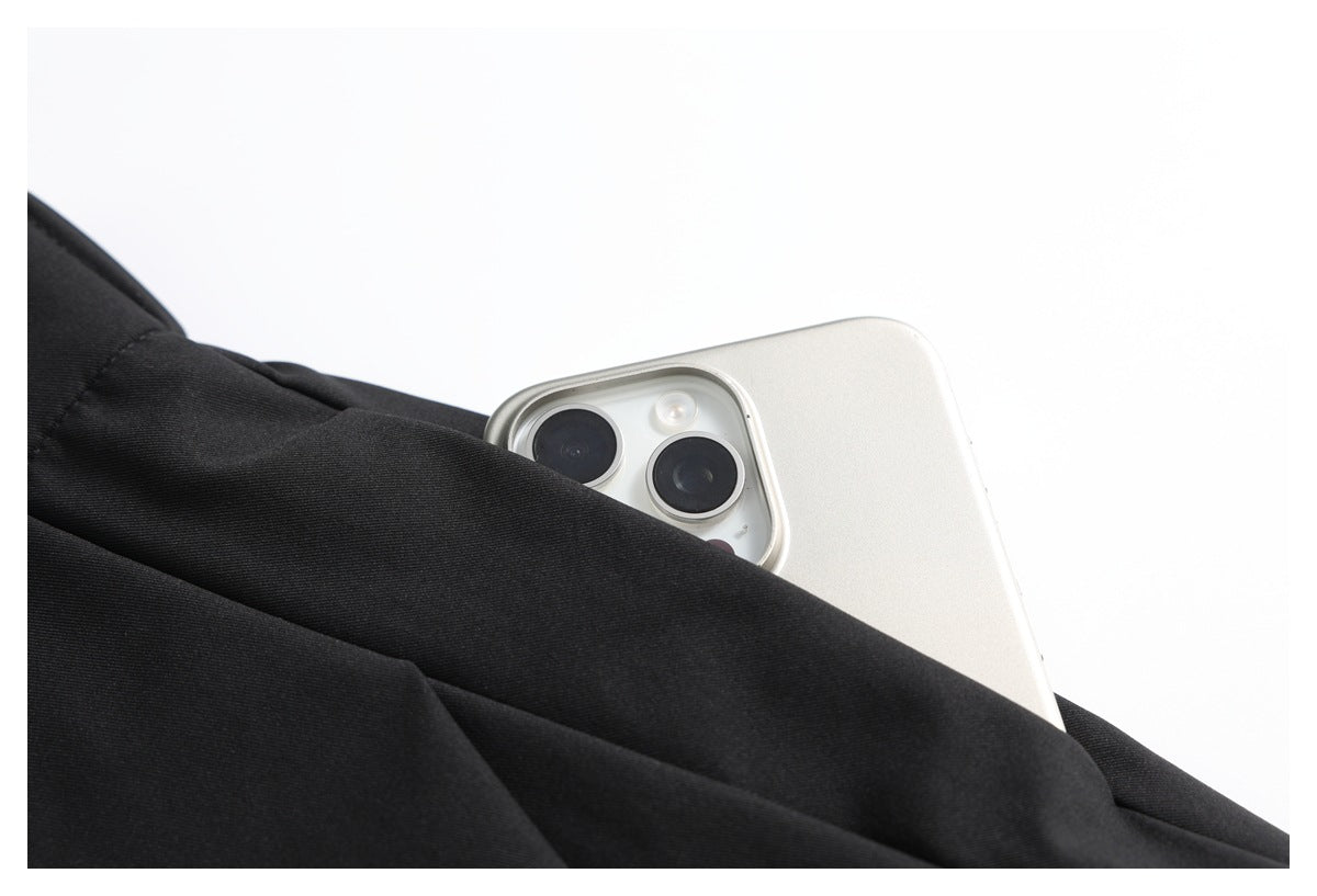 A white smartphone is partly tucked into a pocket on black trousers.