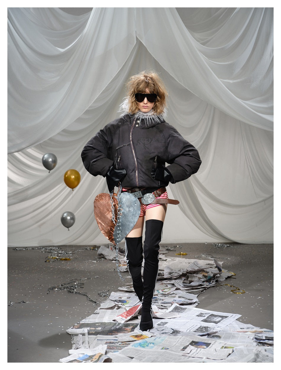 Front view of a model wearing a dark fur-trimmed hooded jacket, striped shorts and black thigh-high boots.