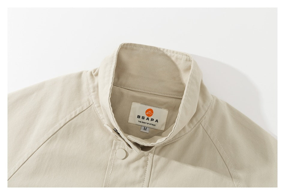 Close-up of a beige jacket's stand collar, snap closure and inner BSAPA neck label.