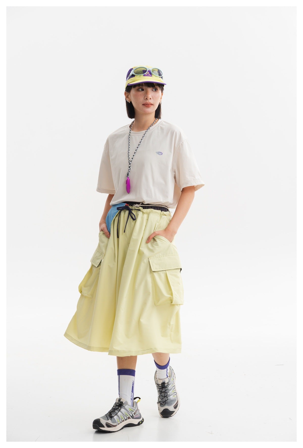 Closer view of a pale yellow cargo skirt with a flared shape, drawstring waist and roomy side pockets, worn by a model.