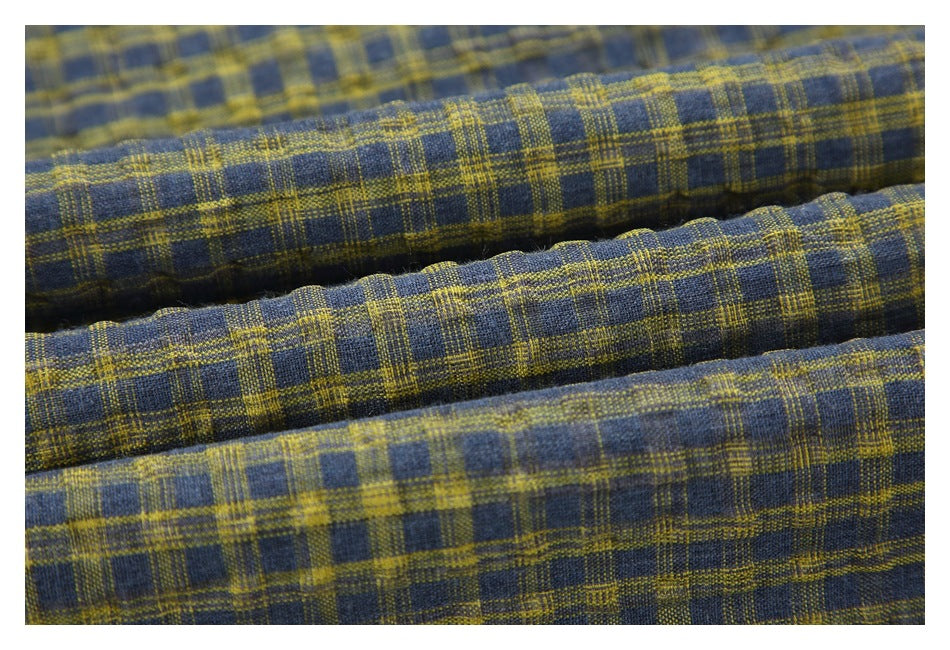 Close-up of folded navy fabric with a mustard-yellow plaid pattern.
