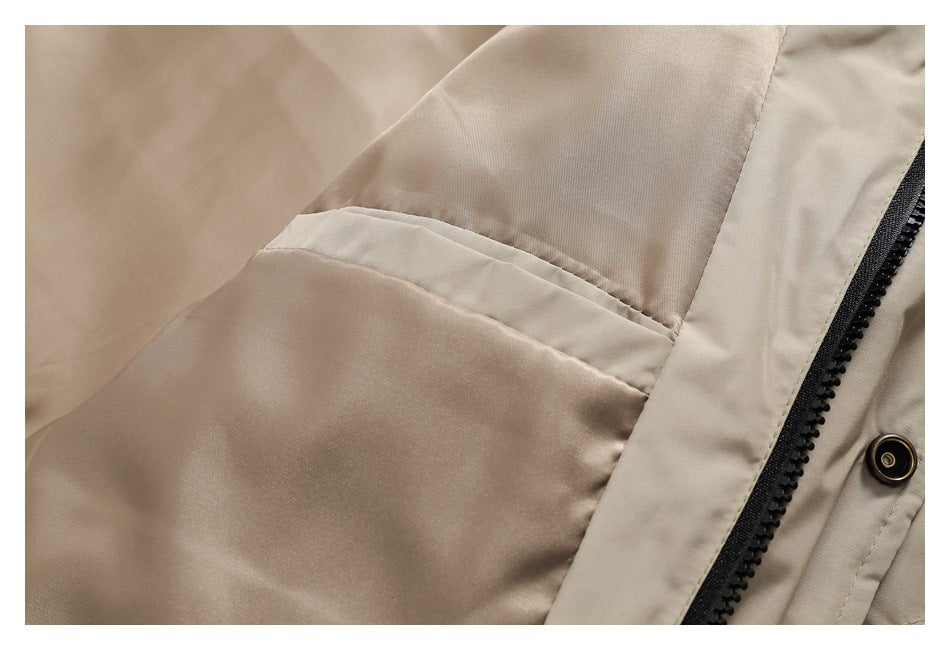Close-up of a beige jacket pocket seam beside a black zipper and snap fastener.