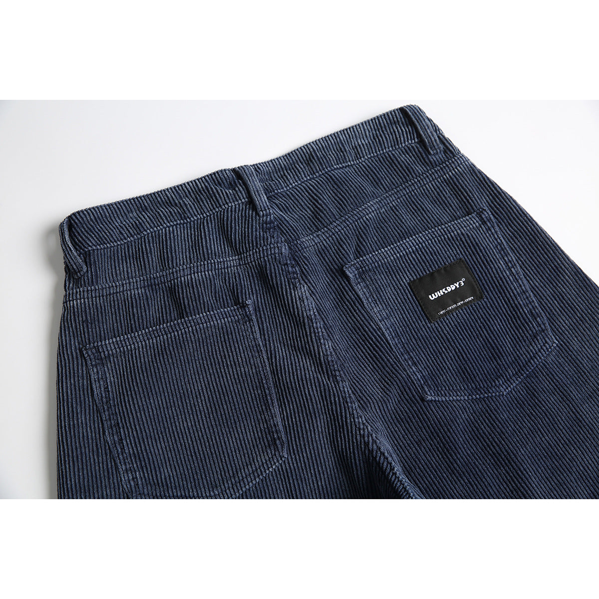 Close-up of the back waistband and patch pockets on navy ribbed pants.