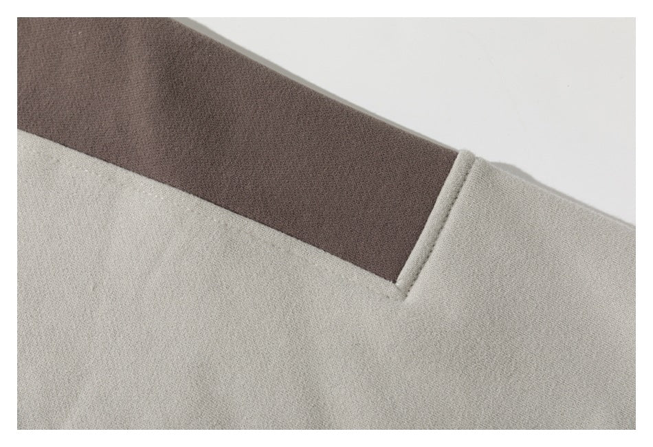 Close-up of a taupe panel across the cream sweatshirt, showing the color-block seam.