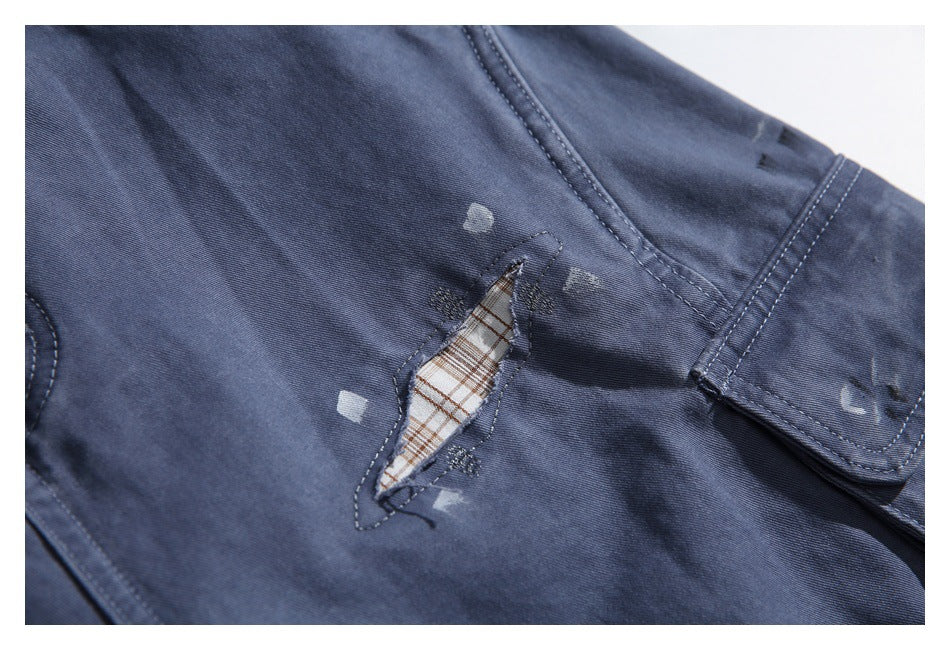 Navy garment detail with a small distressed opening revealing plaid fabric beneath.