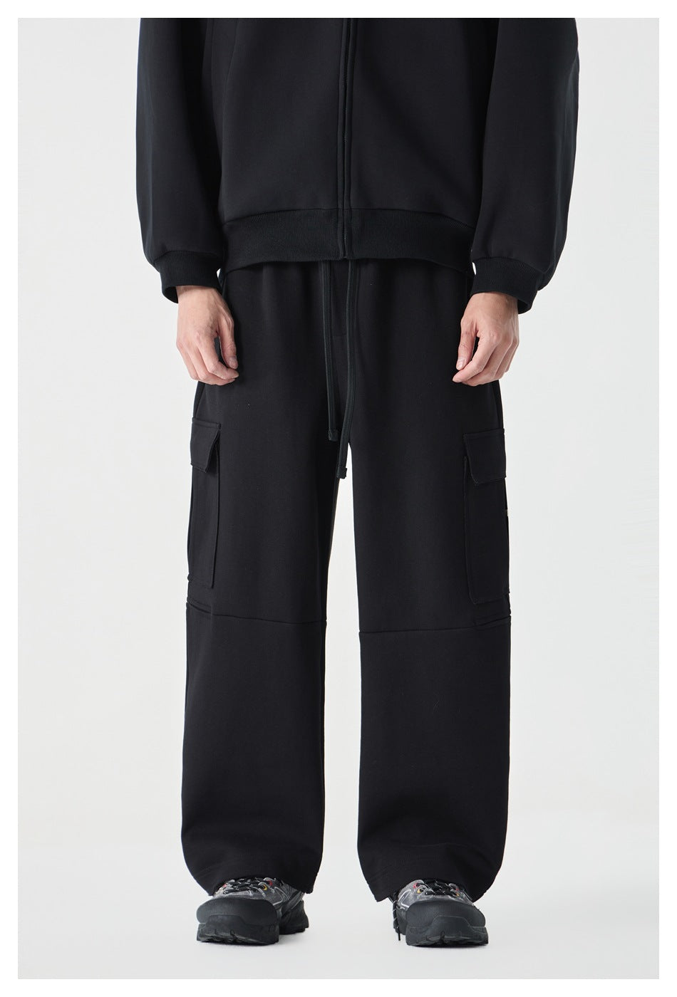 Front view of a cropped model in black wide-leg cargo pants with side flap pockets and a drawstring waist.