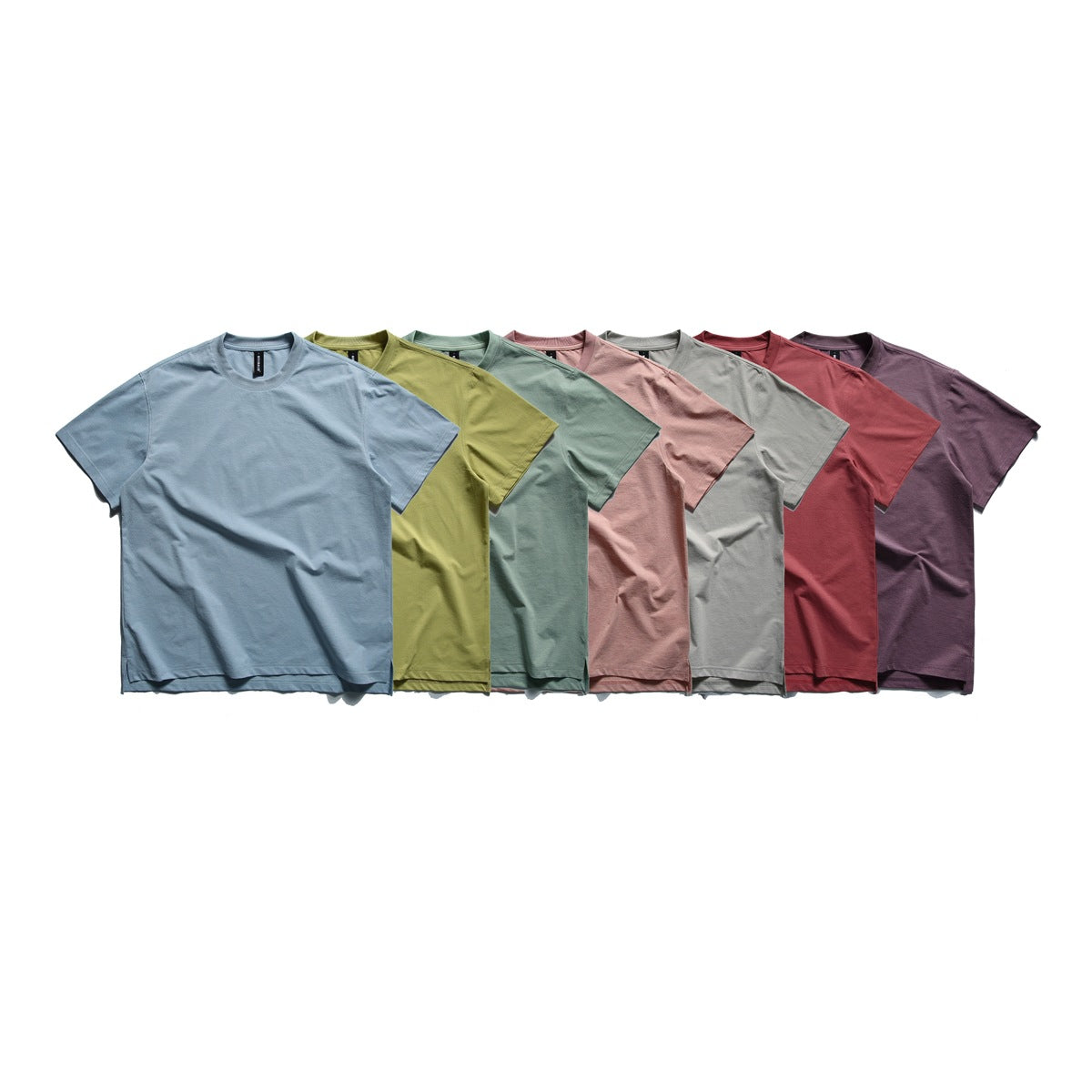 Seven short-sleeve crew-neck T-shirts arranged together in blue, olive, sage, pink, gray, red and plum.