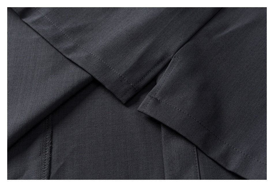 Close-up of overlapping dark charcoal garment panels showing seams and stitched hems.