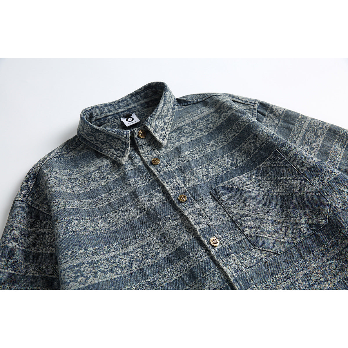 Flat-lay view of a blue patterned button-up shirt with a pointed collar, chest pocket, and brass-tone buttons.