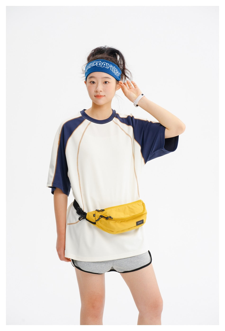 Closer view of a model wearing a cream tee with navy raglan sleeves and contrast stitching, with gray shorts and a yellow