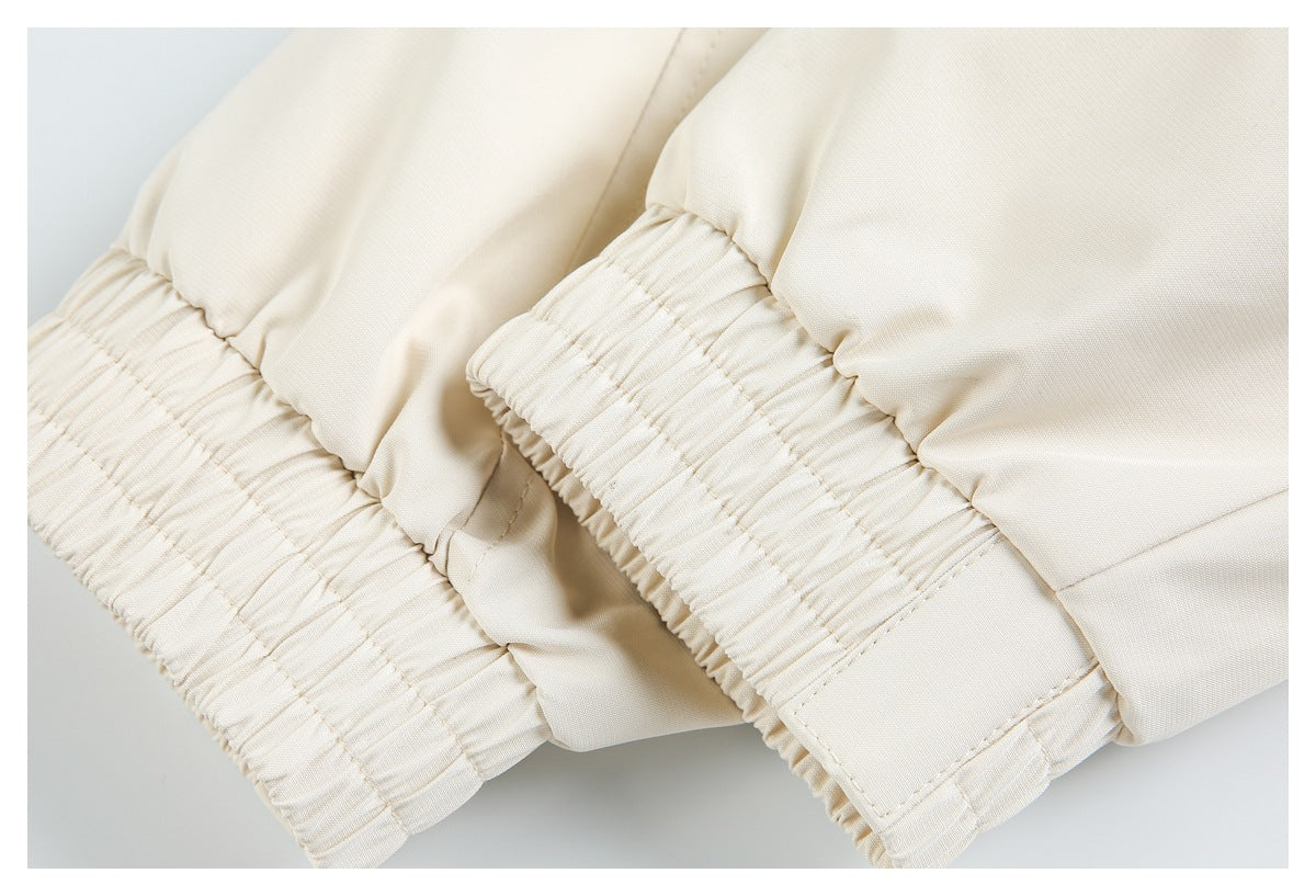 Close-up of ivory garment with two gathered elastic edges and visible stitching.
