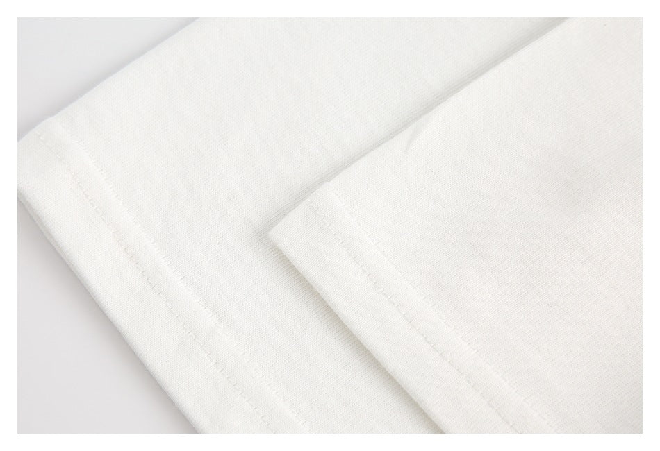 Close-up of folded white fabric showing stitched edges and a fine knit texture.
