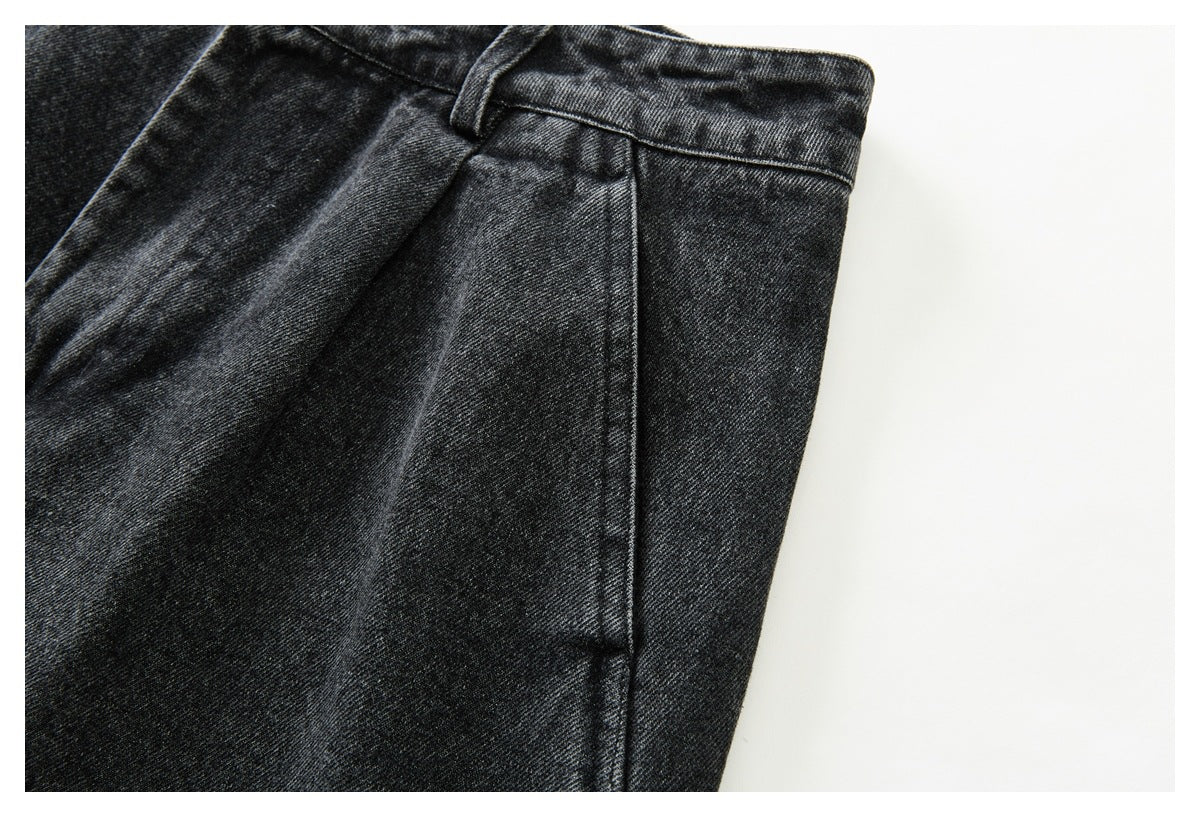 Close-up of the side seam and pocket area beneath the waistband of black washed denim trousers.
