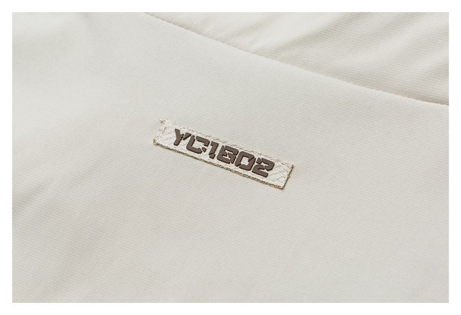 Close-up of a small dark embroidered label on light beige garment fabric.