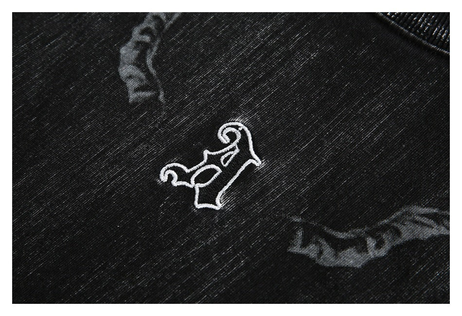 Close-up of a white embroidered emblem on black fabric with gray graphic accents.