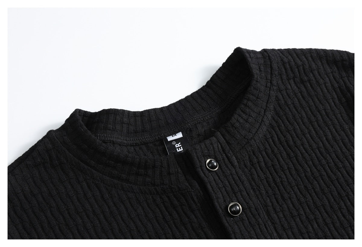Close-up of a black ribbed shirt's stand collar, placket, and two dark buttons.