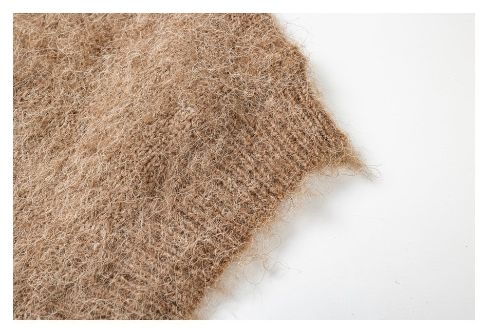 Close-up of a brown fuzzy knit garment edge against a white background.