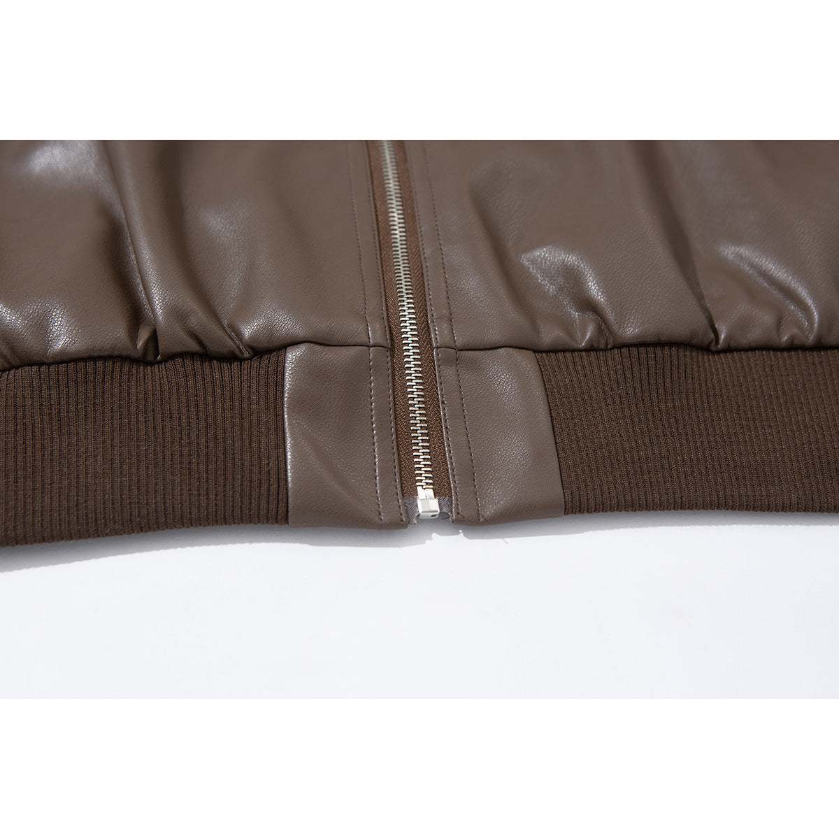 Close-up of the brown jacket's ribbed hem and silver front zipper.
