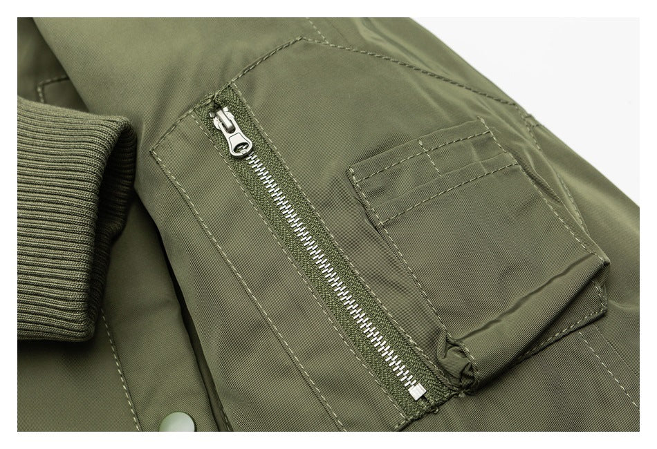 Close-up of an olive jacket's zippered sleeve pocket and stitched utility pocket.