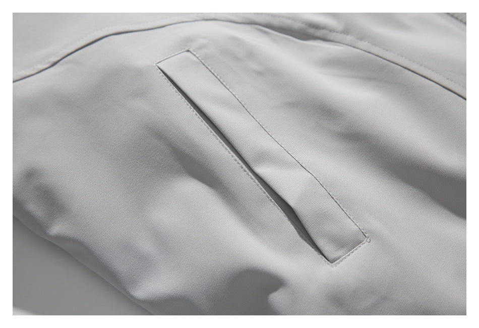 Close-up of a light gray garment showing a narrow welt pocket and neat stitching.