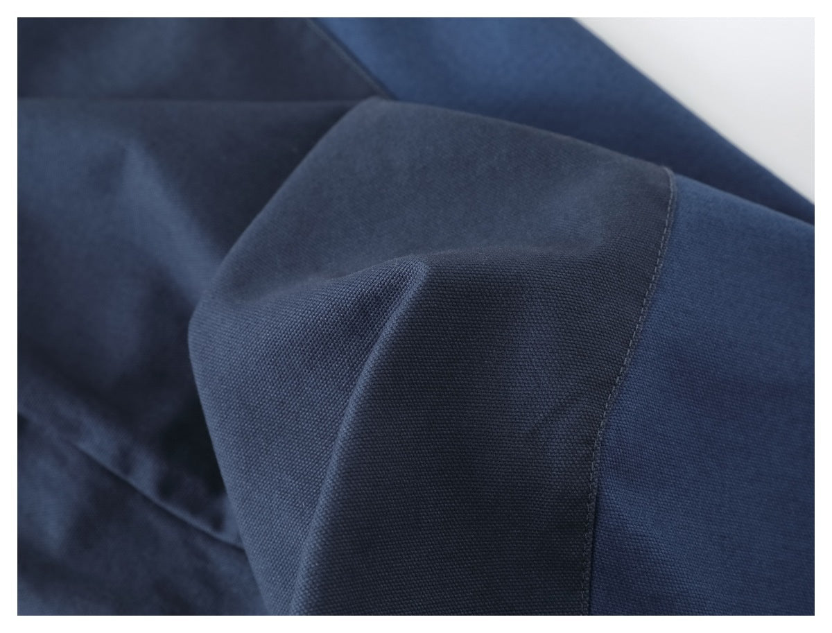 Macro view of navy garment fabric, showing its woven texture and stitched panel seam.