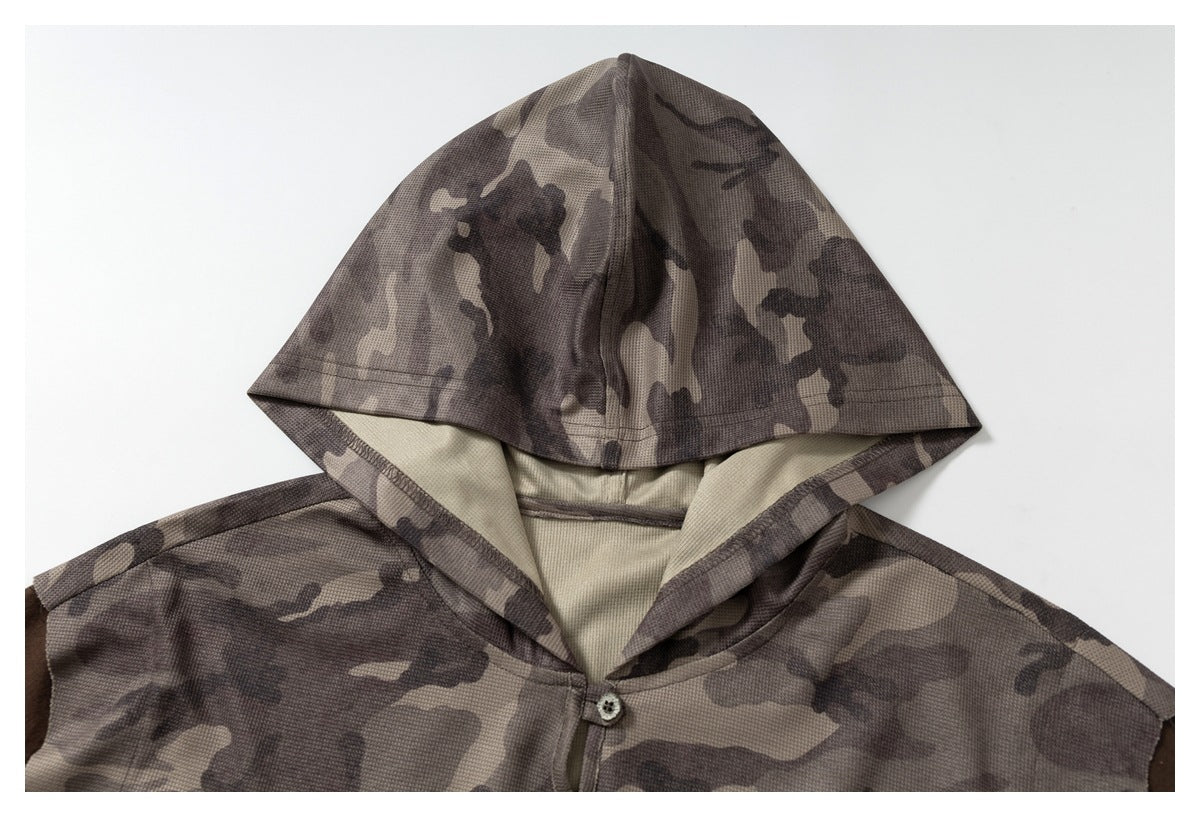 Close-up of the camouflage hood, light lining, and buttoned neckline on the shirt.