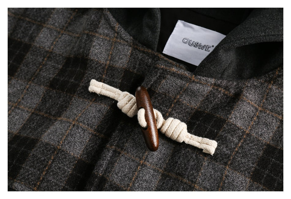 Close-up of a rope-and-wood toggle closure on the coat's plaid fabric, with the inner label visible.